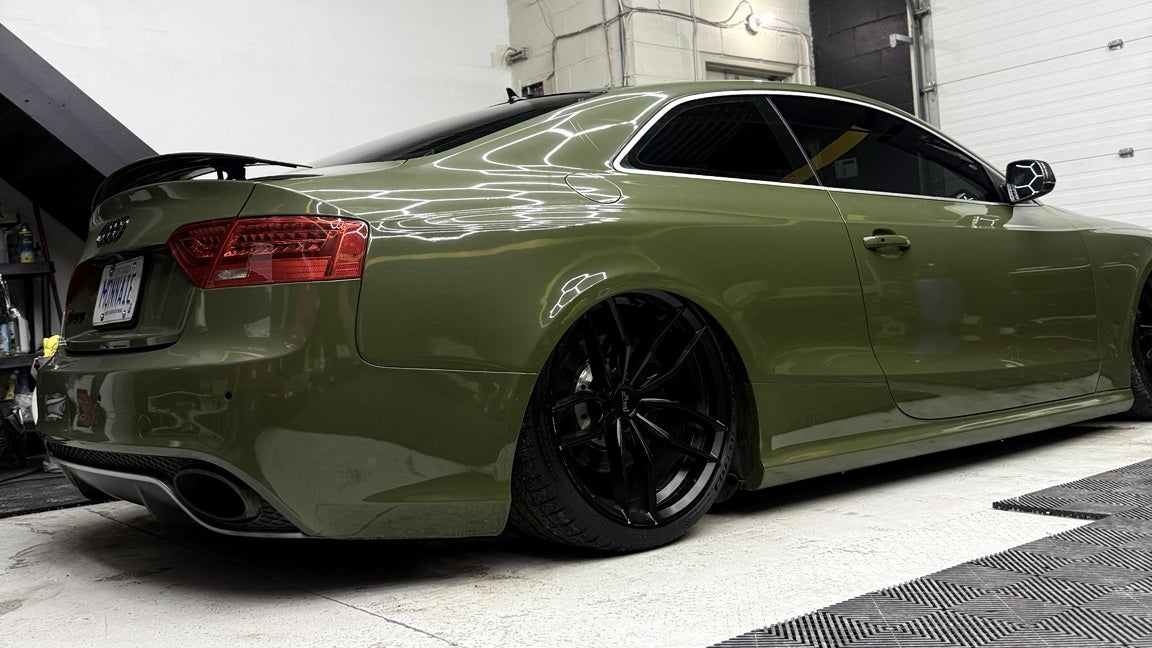 Image of Olive-green 2015 Audi RS5 B8.5 aired out on ONAIR suspension, viewed from the rear quarter on black wheels.