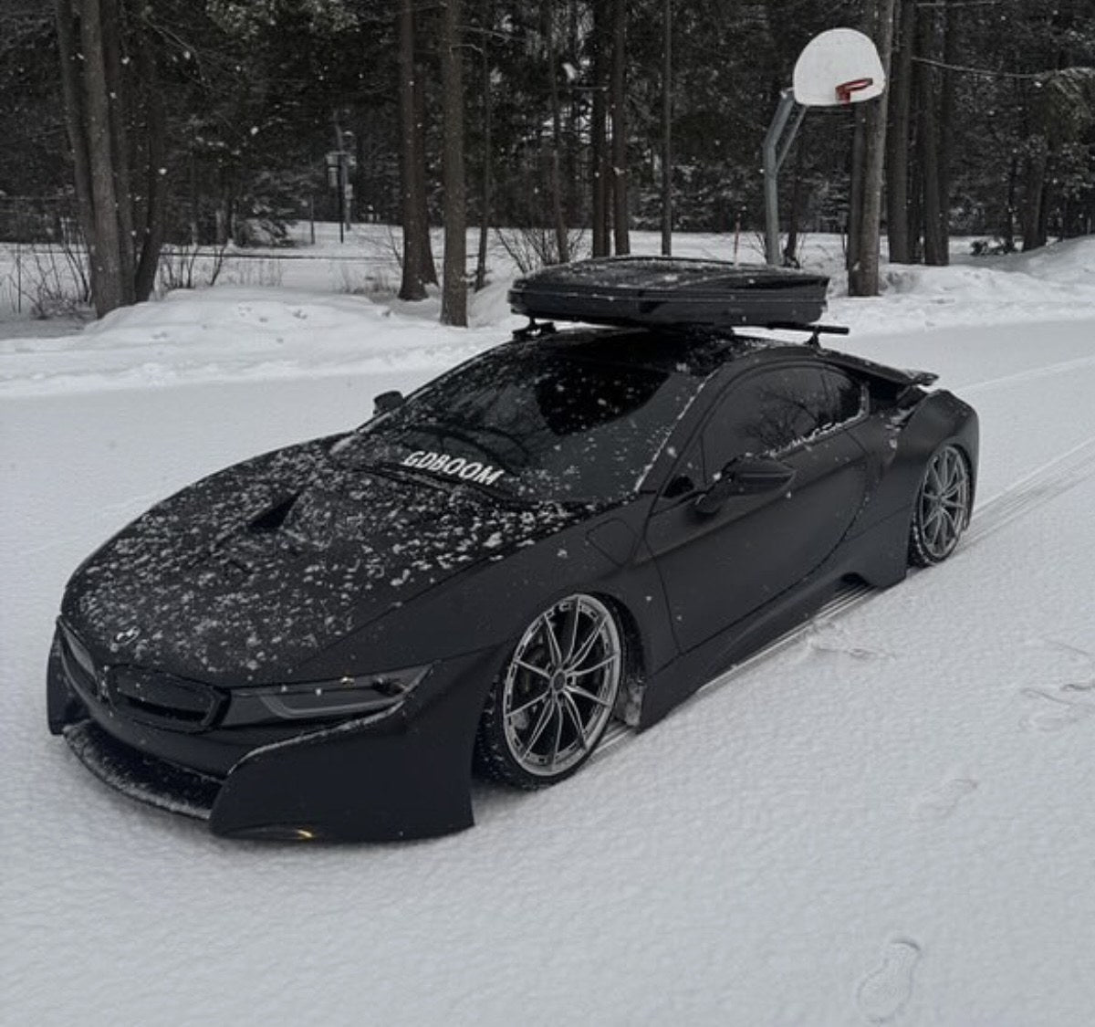 Image of Black BMW i8 with a roof cargo box parked on a snow-covered court.