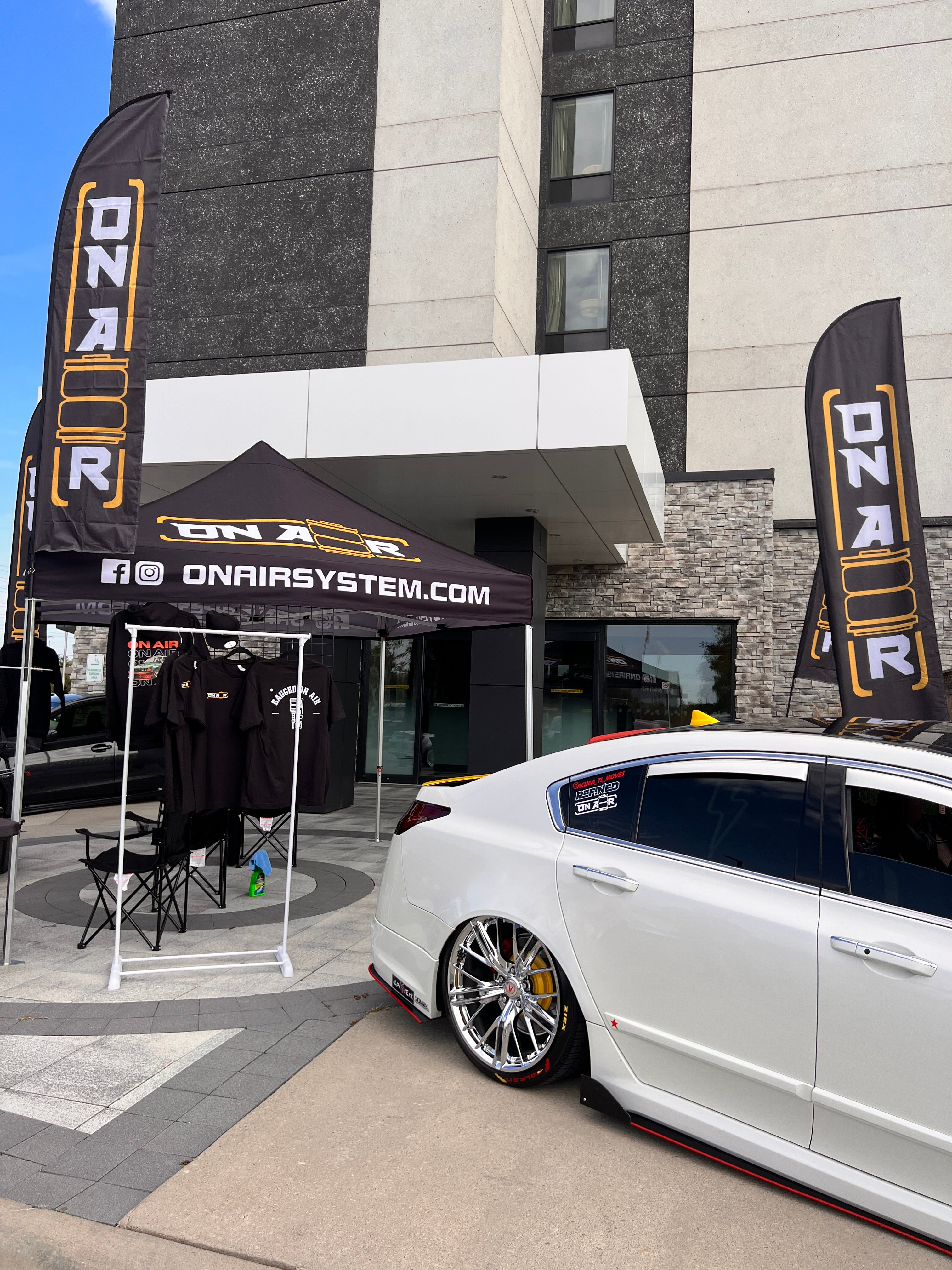 Image of Photo showing the onair canopy, onair flags, some onair merch, all complimented with a bagged acura tl all infront of a hotel